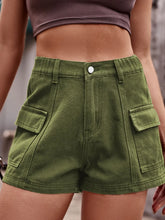 Woman in a cream-colored sweater and matcha green Joyful Journey Denim shorts tending to plants in a garden.