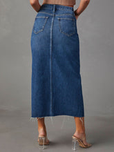 Back view of medium blue Denvara Raw Hem Front Slit Denim Midi Skirt showcasing back pockets and raw hem
