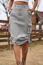 Mid gray Rovelle Cargo Skirt front view with hands in side pockets, ranch backdrop