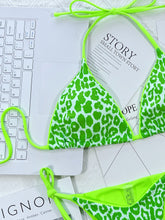 Close-up flat lay detail of hot mint green leopard print tie side bikini set showing halter neck and side tie string details