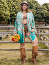 Model in Miravellea turquoise floral kimono cover-up styled with camel shorts, cowgirl hat, and boots