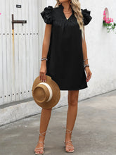 Model posing in front of flower a flower shop wearing a straw hat and  Calivémuse™ ruffled cap sleeve dress in black styled with jewelry and spaghetti strap sandals.