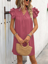 Model front viiew in Dusty Pink ruffled notched cap sleeve mini dress with a straw handbag at a garden party.