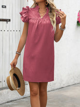 Lady posing with a straw hat wearing the dusty pink ruffled notched cap sleeve dress.