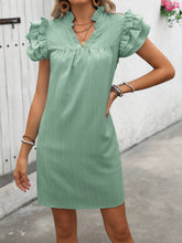 Model front view wearing the sage Calivémuse™ ruffled notched cap sleeve mini dress styled with accessories.
