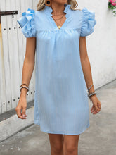 Model wearing the pastel blue ruffled notched cap sleeve mini dress at a casual evening brunch.