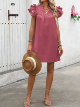 Model posing with a straw hat wearing the dusty pink ruffled notched cap sleeve mini dress.