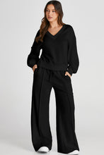 Model lounging on sofa in Black MotoLux Vesper set, relaxed at-home style.