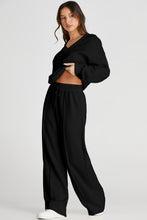 Side view of model doing leg stretch in Black MotoLux Vesper set.