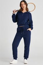 full body front view navy Navaro Duo styled with tennis racket highlighting tapered leg