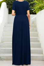 Back view of a model in the navy blue Blissurella Maxi Tee Dress paired with accessories for a relaxed, sunlit afternoon look.