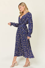 Model side view highlighting tie waist, plunge V-neck, long sleeves, midi length, and fabric quality of Flounce & Tie Midi dress in Navy.