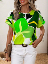 Model wearing a Neon Green contrast round neck short sleeve blouse, paired with light-wash jeans and subtle jewelry for a fresh, casual daytime look.