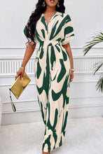 Model in Dark Green Oléavia Luxe Jumpsuit strolling barefoot in a lush garden setting.