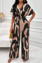 Model wearing the Oléavia Luxe Jumpsuit in Taupe, showcasing the printed design and cinched waist.
