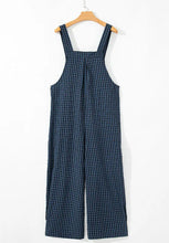 Back view of plaid wide-leg overalls on hanger showing adjustable wide straps.