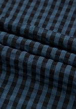 Close-up flatlay of dark blue plaid fabric showing soft texture and color detail.