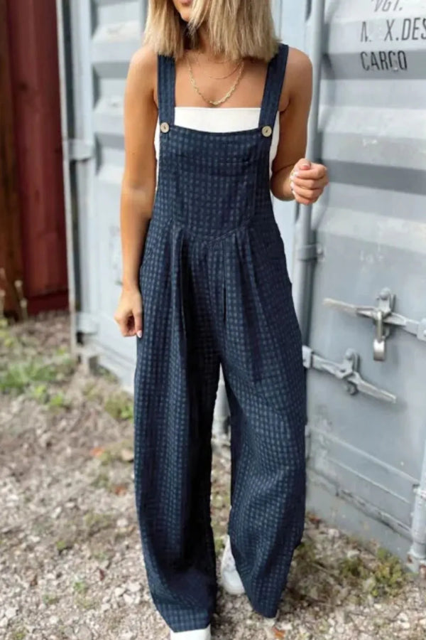 Model wearing dark blue plaid wide-leg overalls front view, styled with a white fitted tee and sneakers.
