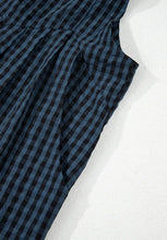 Detail shot of side pocket stitching and plaid fabric pattern.