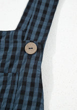 Flatlay detail of wide strap with polished button attachment.