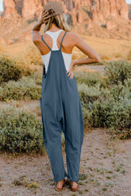 Model showing back view of Onvaira V-neck sleeveless jumpsuit in peacock blue.