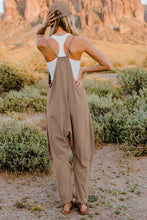 Model showing back view of Onvaira V-neck sleeveless jumpsuit in tan.