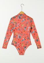 Orange Printed Mock Neck Long Sleeve Bodysuit hanging on a hanger, showing off the bold abstract design and high neckline against a light backdrop.