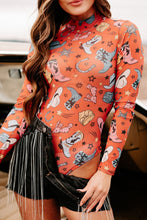 Model wearing a Printed Mock Neck Long Sleeve Bodysuit in orange with trendy abstract print, paired with black distressed jean shorts, standing ouside of a cafe.