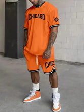 Model wearing a oversized dark orange Orrik 3D Printed Motion Set with 'Chicago' text on orange round neck tee and dark orange shorts with 'Chicago' on them.
