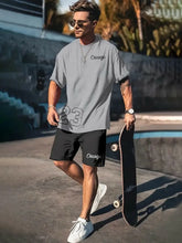 Man wearing a oversized grey Orrik 3D Printed Motion Set with 'Chicago 23' text on grey round neck tee and black shorts with 'Chicago' on them.