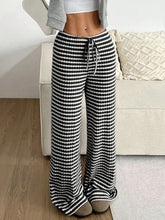 Female model in Black Orvella LumaTide Striped Wide Leg Pants paired with a grey short-sleeved blouse, jewelry, and camel loafers.