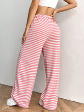 Back view of Blush Pink Orvella LumaTide Striped Wide Leg Pants paired with a white blouse, jewelry, and white sneakers.