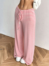 Side view of Blush Pink Orvella LumaTide Striped Wide Leg Pants styled with a white blouse, white handbag, and white sneakers.