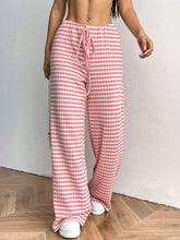 Blush Pink Orvella LumaTide Pants paired with a white blouse, jewelry, and white sneakers for chic casual wear.