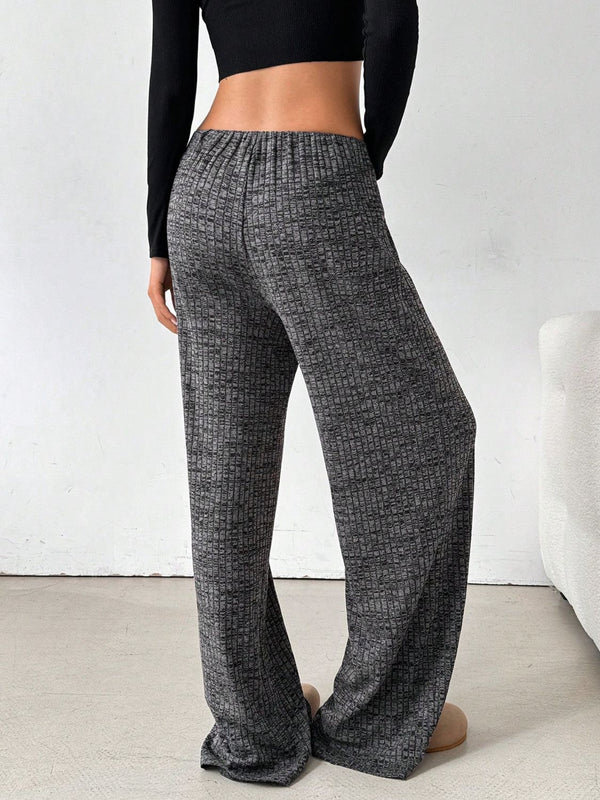 Back view of female model in Dark Grey Orvella LumaTide Striped Wide Leg Pants, paired with a black long-sleeved blouse, jewelry, black purse, and light brown boots.