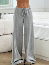 Female model in Grey Orvella LumaTide Striped Wide Leg Pants paired with a white short-sleeved blouse, jewelry, and camel loafers.