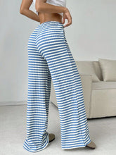 Back view of Light Blue Orvella LumaTide Striped Wide Leg Pants styled with a white short-sleeved blouse, jewelry, white purse, and camel boots.