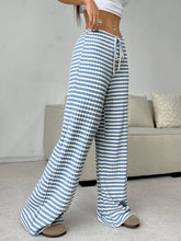 Side view of Light Blue Orvella LumaTide Striped Wide Leg Pants paired with a white long-sleeved blouse, jewelry, and camel loafers.