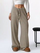 Female model in Taupe Orvella LumaTide Striped Wide Leg Pants styled with a white short-sleeved blouse, jewelry, and brown boots.