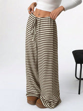 Side view of Taupe Orvella LumaTide Striped Wide Leg Pants styled with a white long-sleeved blouse, jewelry, and camel loafers.