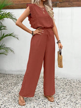 Model wearing the Papiloniya™ Lace Trim Round Neck Top and Pants Set in Terracotta. Featuring lace trim top and wide-leg pants, styled with a straw handbag and sandals.