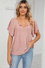 Woman in a peach Veluretta Mistflair Blouse sipping coffee at a city café.