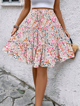 Model posing in pink Florévyn Floral Print Midi Skirt featuring frill tiers and ruffled hem