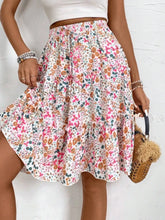 Side view of pink Florévyn Floral Print Midi Skirt with decorative waist tie, frill tiers, and ruffled hem
