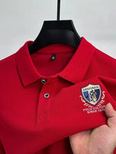 Close-up front view of red Equestrian Crest Designer Polo on hanger showing embroidery, buttons, and flip color-contrast collar.