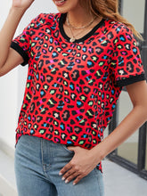 Close-up of red leopard print fabric, showing soft, lightweight texture with bold black and deep red animal print pattern.