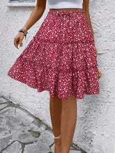 Red Florévyn Floral Print Midi Skirt walking view styled with white tube top, highlighting frill tiers and ruffled hem