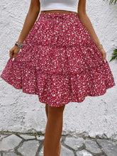 Model posing in red Florévyn Floral Print Midi Skirt featuring frill tiers and ruffled hem