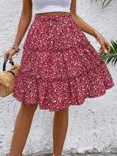 Side view of red Florévyn Floral Print Midi Skirt with decorative waist tie, frill tiers, and ruffled hem
