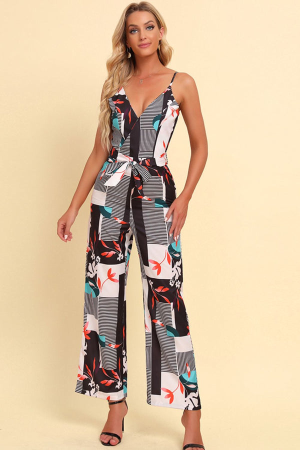 Model wearing the Rexéa white floral jumpsuit with spaghetti straps and a waist tie, standing in a sunlit garden.